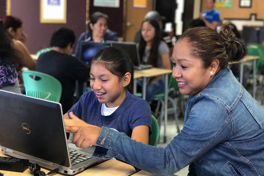 hispanic girls and female educator working on a laptop in a classrooom setting