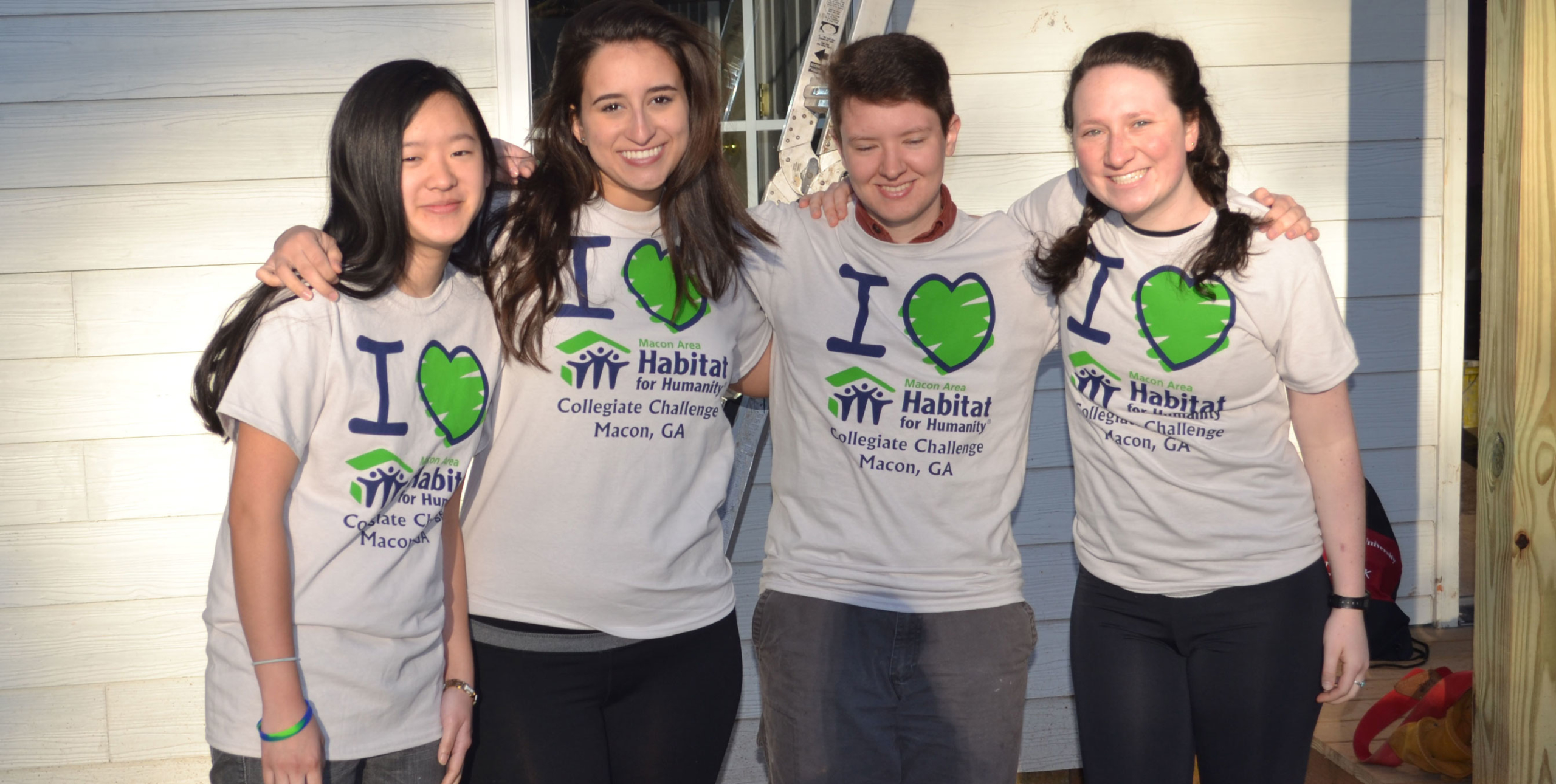 four young children wearing matchign t shirts., smiling and representing habitat for humanity